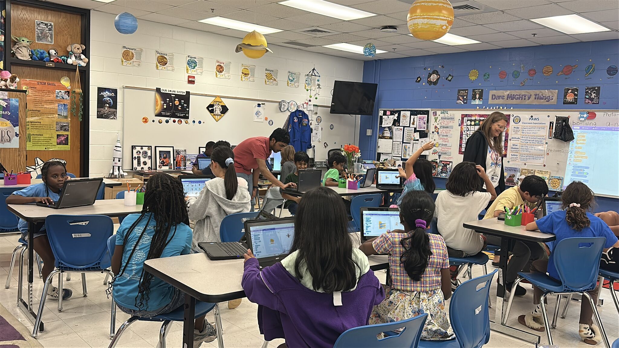A full classroom of elementary students working on Scratch projects during a workshop
