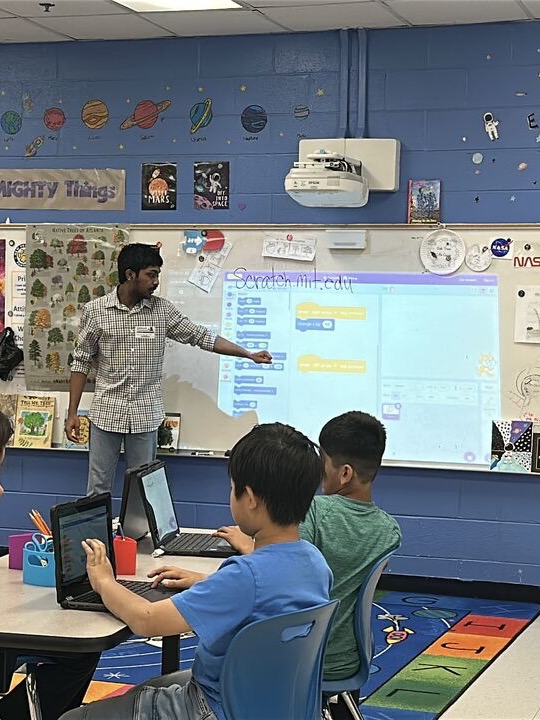 Volunteer teaching Scratch programming to elementary students in a STEM classroom